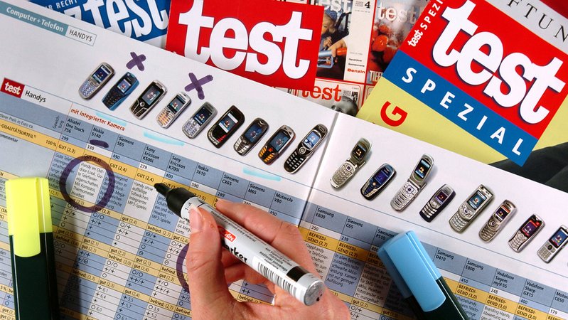 (Symbolbild) Blick auf eine Tabelle von Stiftung Warentest zu Handys. Eine Hand markiert mit einem Filzstift bestimmte Modelle. | Bild: pa/dpa/Jens Büttner (Symbolbild) Blick auf eine Tabelle von Stiftung Warentest zu Handys. Eine Hand markiert mit einem Filzstift bestimmte Modelle.