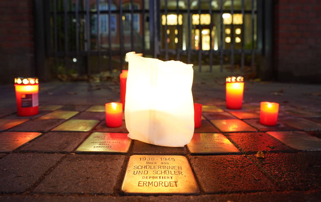 Kerzen stehen an Stolpersteinen bei der Gedenkfeier an die Pogromnacht. 