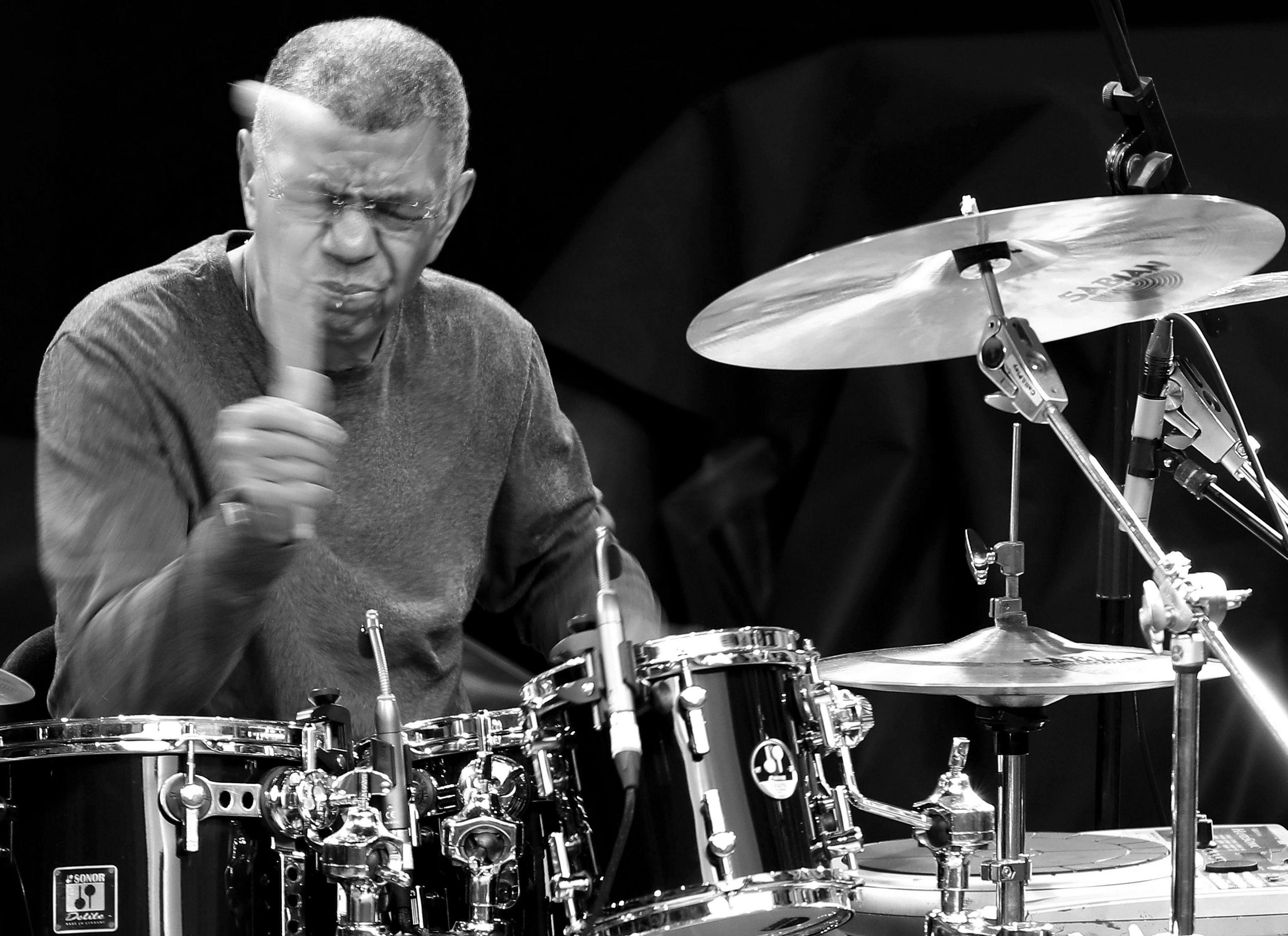 Schwarz-Weiß-Aufnahme von Jazz-Legende Jack DeJohnette, er spielt Schlagzeug, die Augen sind geschlossen.
