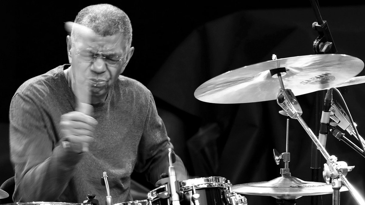 Schwarz-Weiß-Aufnahme von Jazz-Legende Jack DeJohnette, er spielt Schlagzeug, die Augen sind geschlossen.