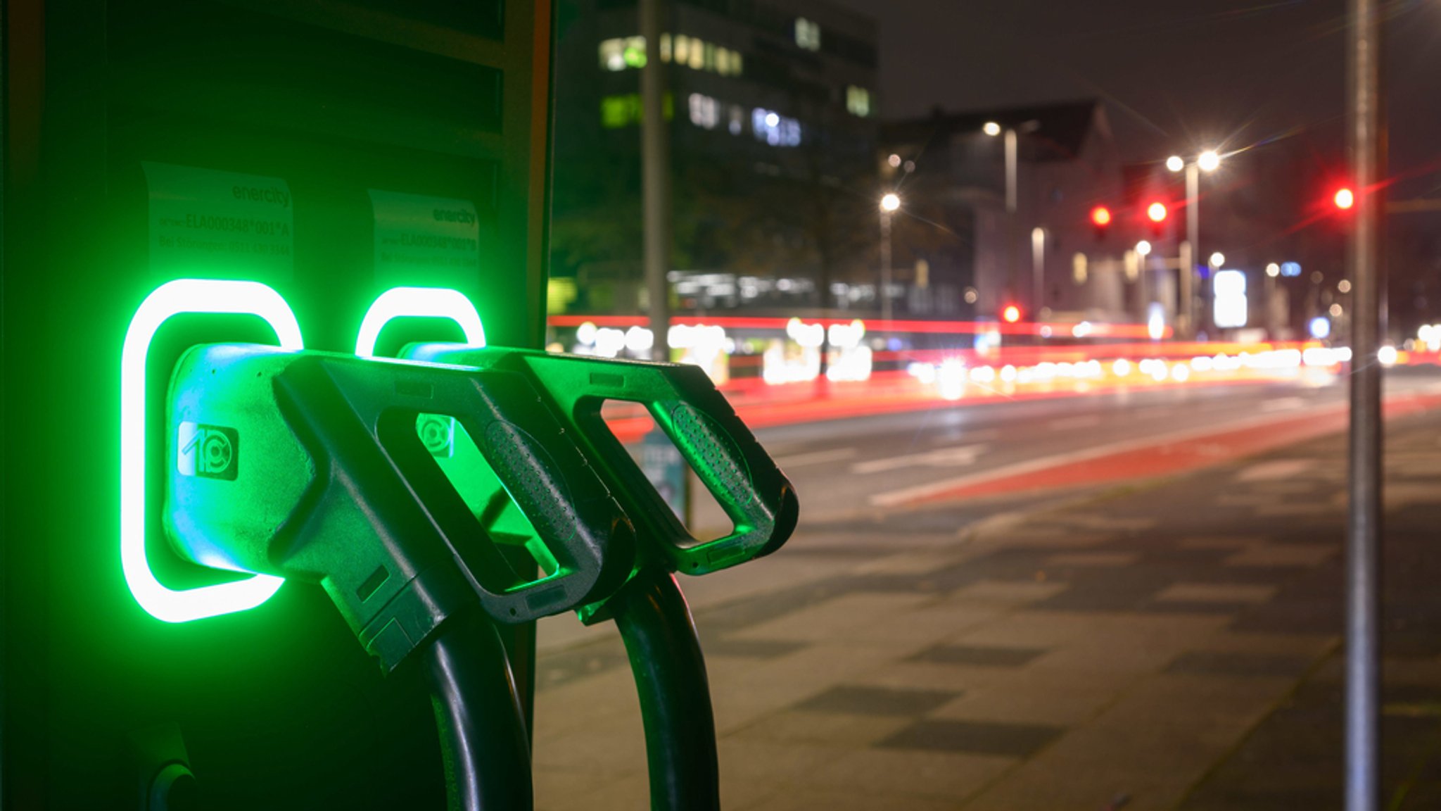 Grün leuchten Ladekabel an einer Schnellladesäule für Elektroautos. 