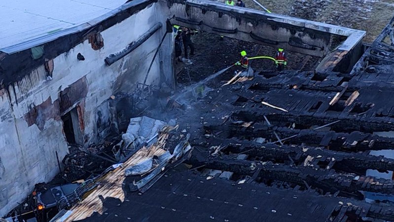 Ein Feuer hat in einer Fahrzeughalle der Bergbahn schwere Schäden angerichtet. Feuerwehrkräfte löschen die Überreste des Brandes | Bild: Bayerischer Rundfunk 2025 Ein Feuer hat in einer Fahrzeughalle der Bergbahn schwere Schäden angerichtet. Feuerwehrkräfte löschen die Überreste des Brandes