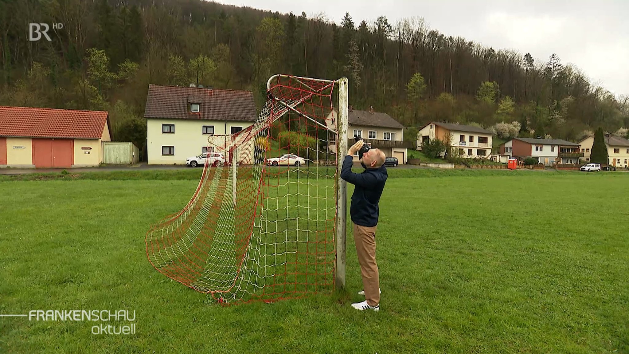 Ein steht vor einem Mann Fußballtor und fotografiert es. 