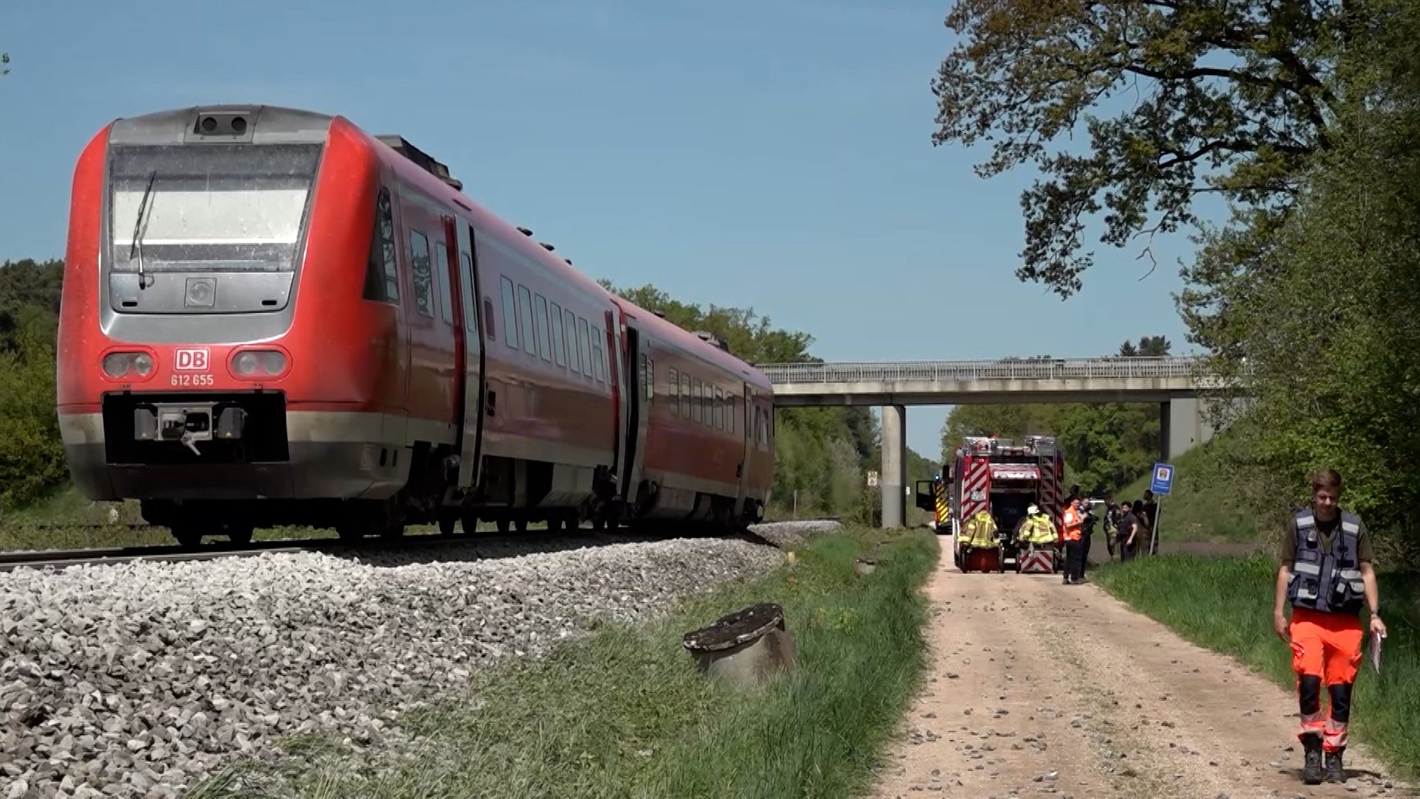 Eine Regionalbahn steht auf einem Gleis im Landkreis Schwandorf. Auf dem parallel verlaufenden Feldweg steht ein Feuerwehrauto, mehrere Rettungskräfte sind zu Fuß unterwegs. 