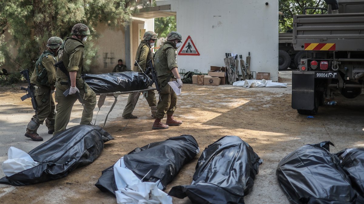 Zwei Ansichten vom Krieg: Israelische Truppen bergen Tote aus einem zerbombten Haus in Kfar Aza..