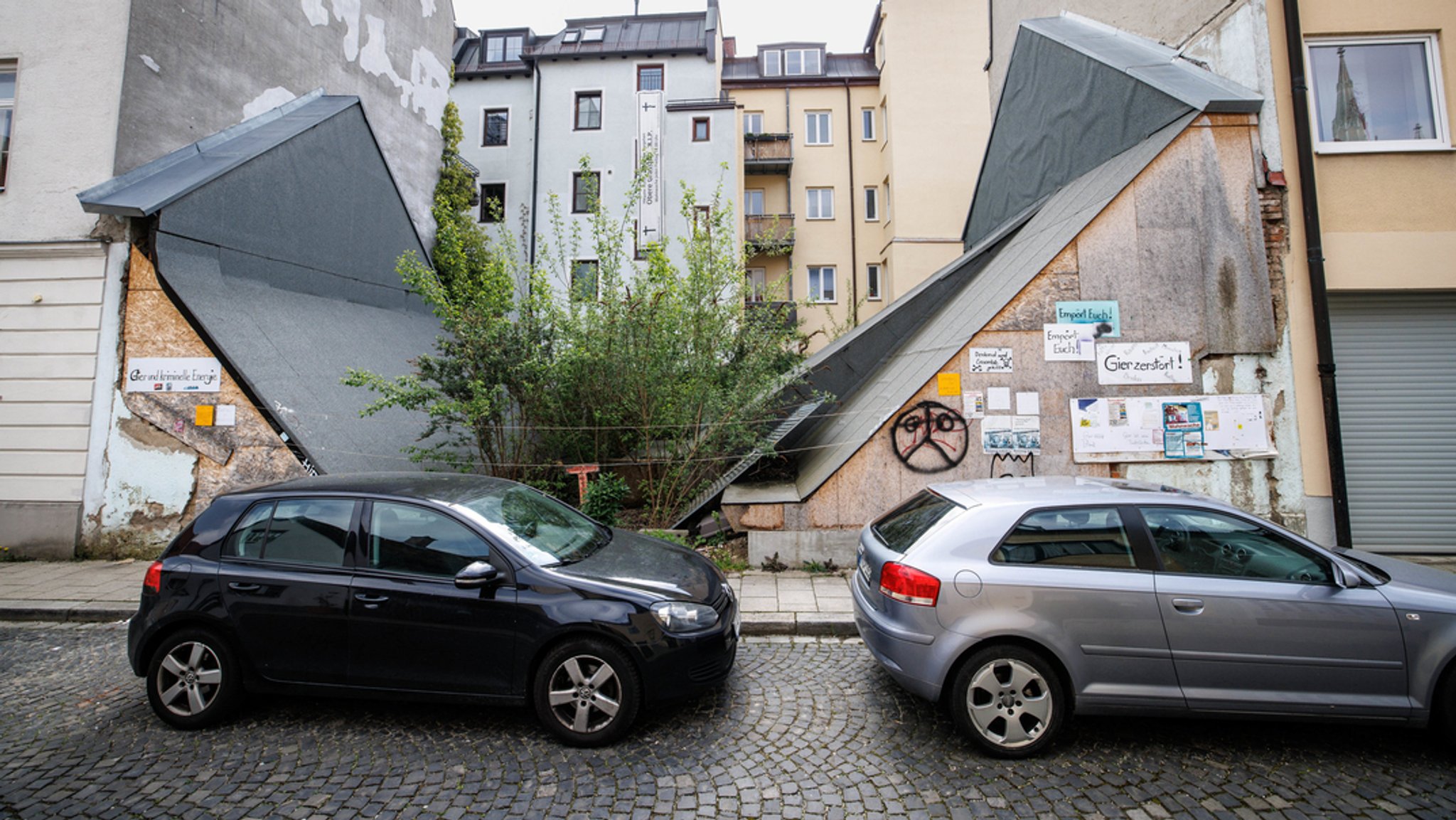 Autos parken vor einer Häuserlücke, in der bis 2017 das denkmalgeschützte Uhrmacherhäusl gestanden hat. Am Amtsgericht hat.