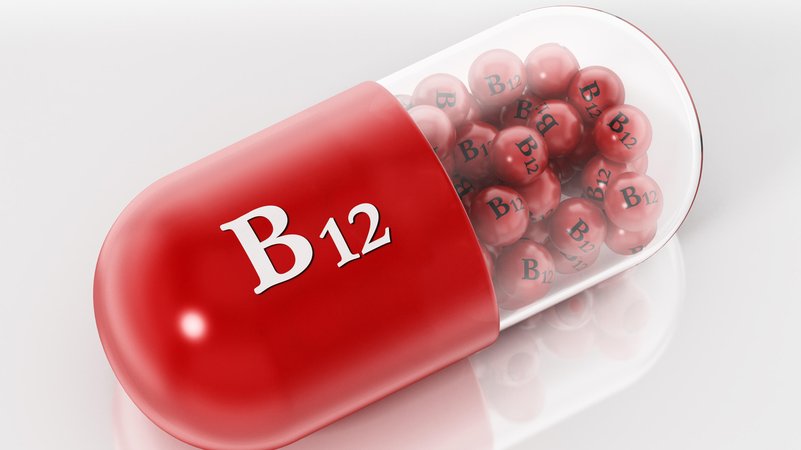 Eine Kapsel (eine Hälfte rot, eine transparent) mit der Aufschrift B12 enthält kleine rote Kügelchen, auf denen B12 steht.