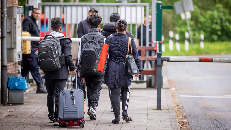 Flüchtlinge mit Gepäck am Eingang eine Ankunftszentrums in Osnabrück