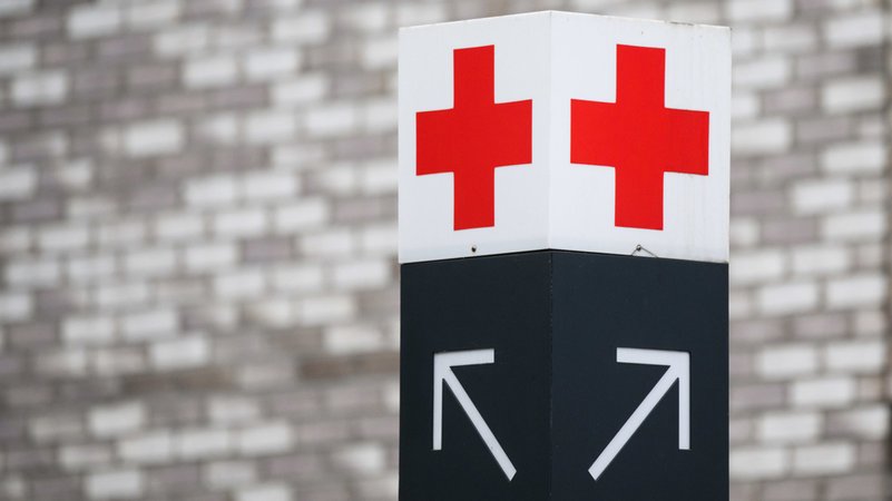 Ein Schild mit einem roten Kreuz weist den Weg zur Notaufnahme.
