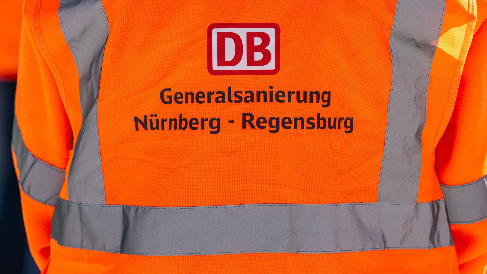 ARCHIV - 29.04.2026, Bayern, Laaber: „Generalsanierung Nürnberg-Regensburg“ steht auf einer Warnweste. Bei einer Halbzeit-Pressekonferenz informierte die Bahn über die Korridorsanierung der Strecke Nürnberg-Regensburg, auf der seit Februar mit rund 80 Baugeräten und bis zu 2000 Beschäftigten gearbeitet wird. (zu dpa: «Bahn: Anfangs Störungen auf modernisierter Strecke möglich») Foto: Armin Weigel/dpa +++ dpa-Bildfunk +++ | Bild: dpa-Bildfunk/Armin Weigel ARCHIV - 29.04.2026, Bayern, Laaber: „Generalsanierung Nürnberg-Regensburg“ steht auf einer Warnweste. Bei einer Halbzeit-Pressekonferenz informierte die Bahn über die Korridorsanierung der Strecke Nürnberg-Regensburg, auf der seit Februar mit rund 80 Baugeräten und bis zu 2000 Beschäftigten gearbeitet wird. (zu dpa: «Bahn: Anfangs Störungen auf modernisierter Strecke möglich») Foto: Armin Weigel/dpa +++ dpa-Bildfunk +++