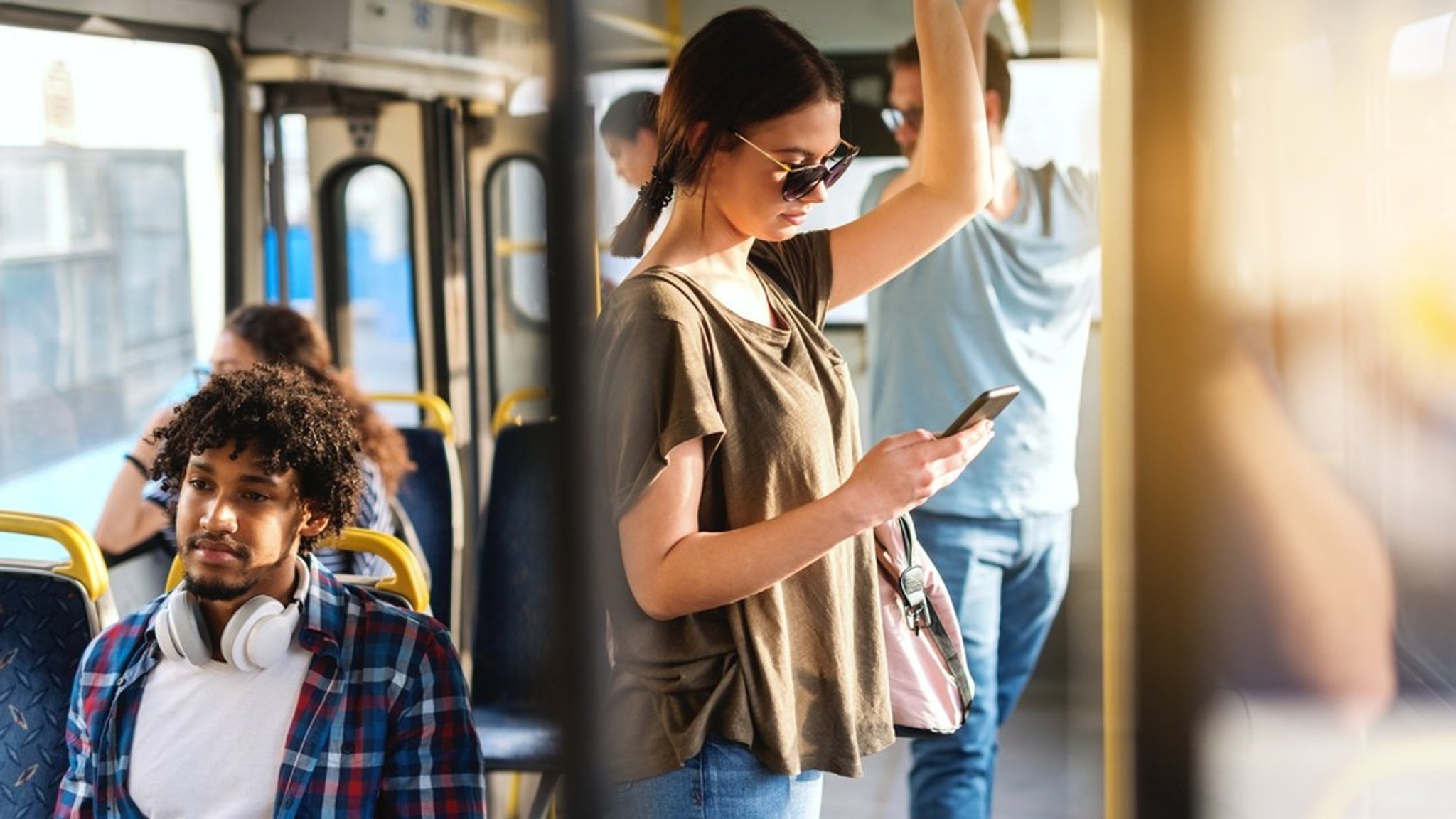 Mehrere Menschen sitzen oder stehen in einem Linienbus.