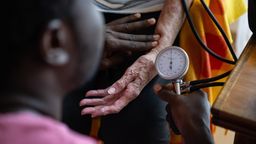 Ein Auszubildender zum Pflegefachmann misst den Blutdruck einer Seniorin. | Bild:picture alliance/dpa/Marijan Murat