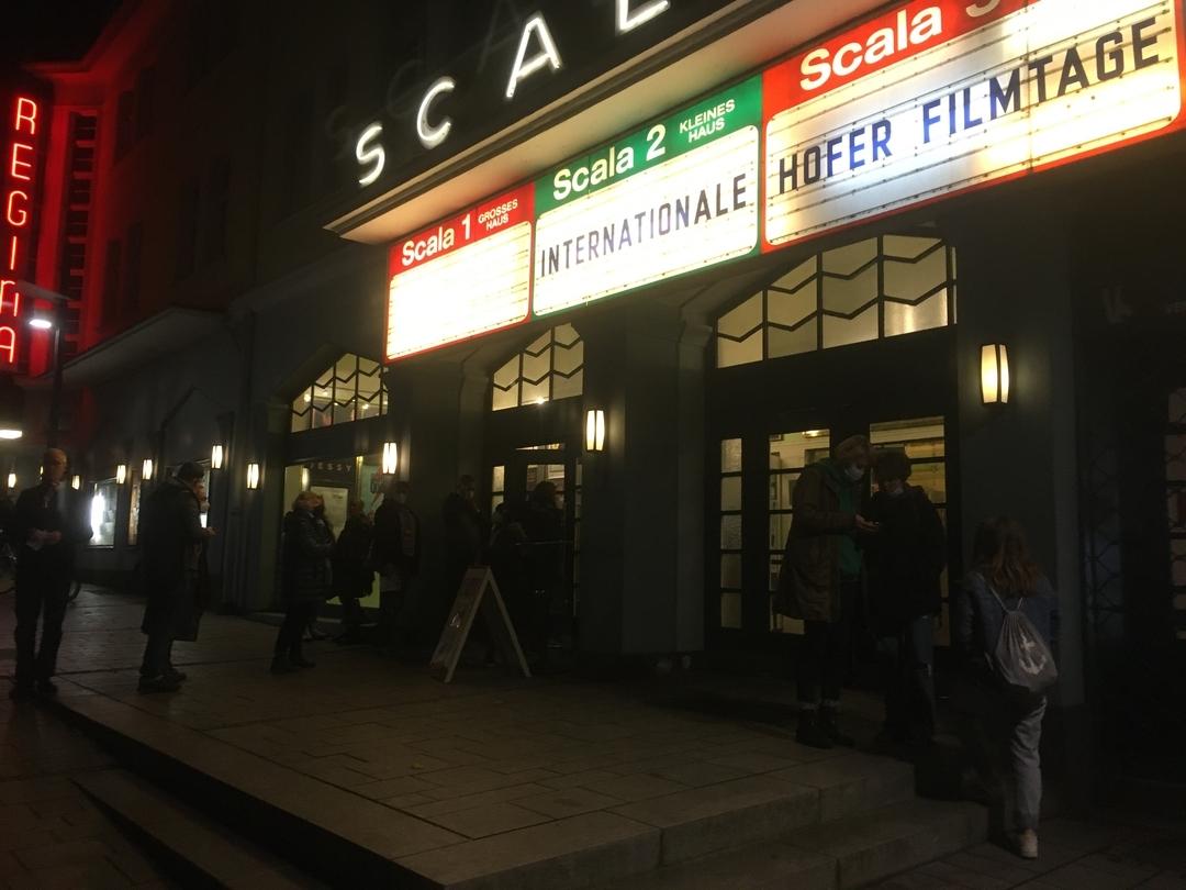 Menschen stehen vor dem Kino "Scala" in Hof. Auf beleuchteten Tafeln steht "Internationale Hofer Filmtage". | Bild:BR/Annerose Zuber