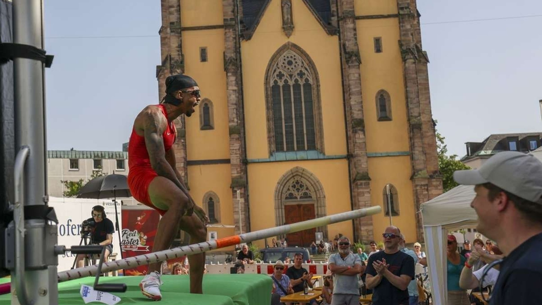 Stabhochspringer Bo Kanda Lita Baehre jubelt. Im Hintergrund sind klatschende Menschen und eine Kirche zu sehen. (Archivfoto)