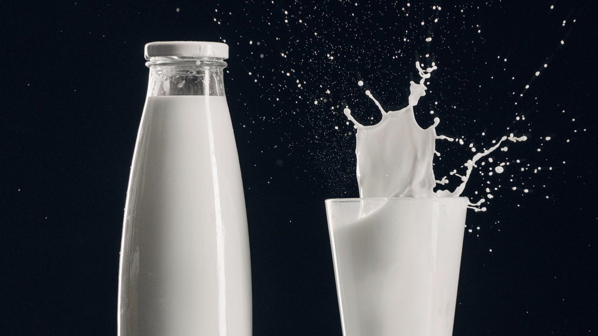 Milchflasche und Glas mit Milch vor schwarzem Hintergrund; Milchersatzprodukte können auch Zusatzstoffe oder Zucker enthalten, die den Gesundheitsnutzen beeinträchtigen können. Es ist wichtig, Milchersatzprodukte sorgfältig auszuwählen und in Maßen zu konsumieren, um von den gesundheitlichen Vorteilen zu profitieren.