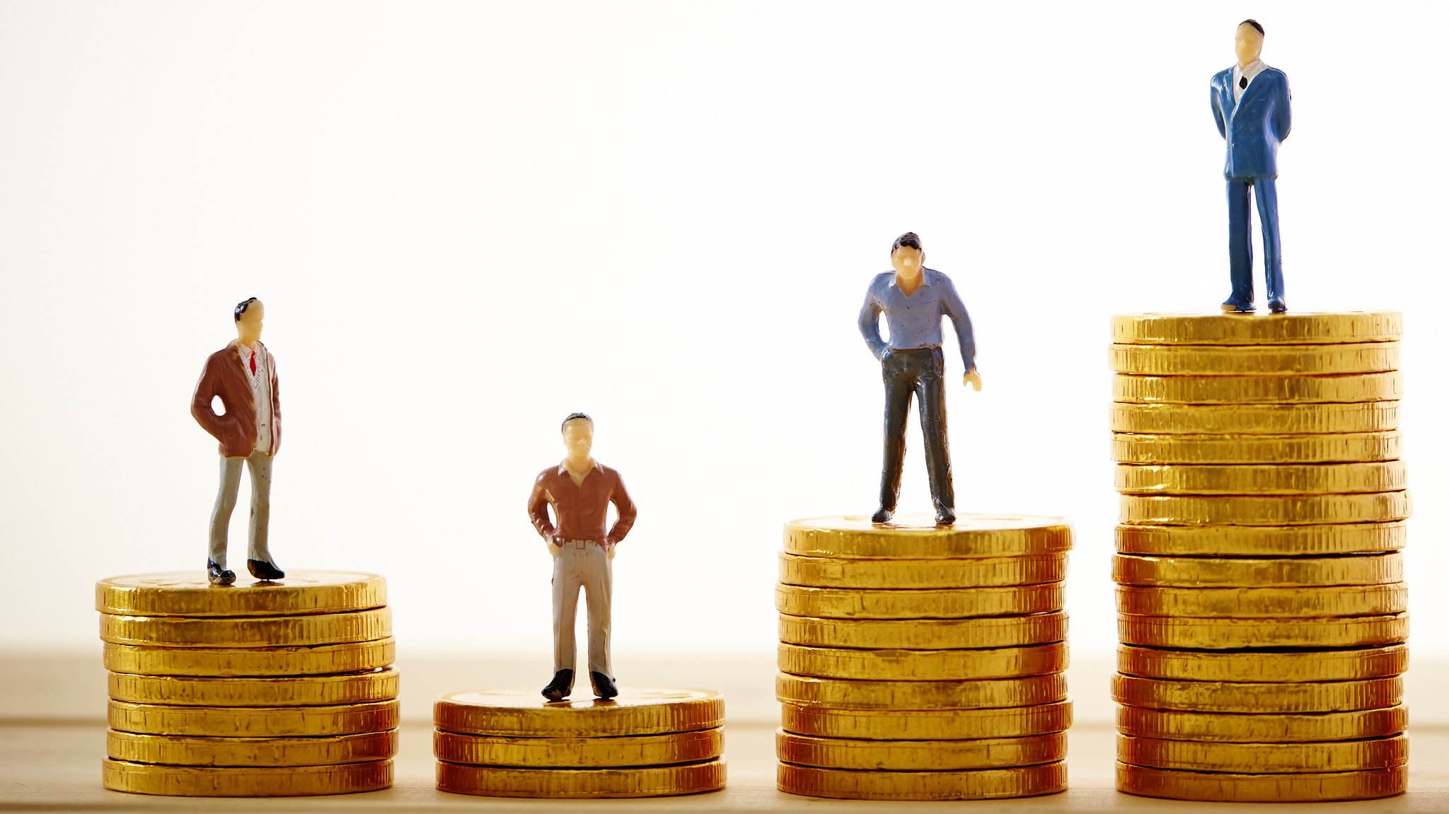 Miniaturfiguren stehen auf unterschiedlich großen Münzhaufen. | Bild: stock.adobe.com Miniaturfiguren stehen auf unterschiedlich großen Münzhaufen.