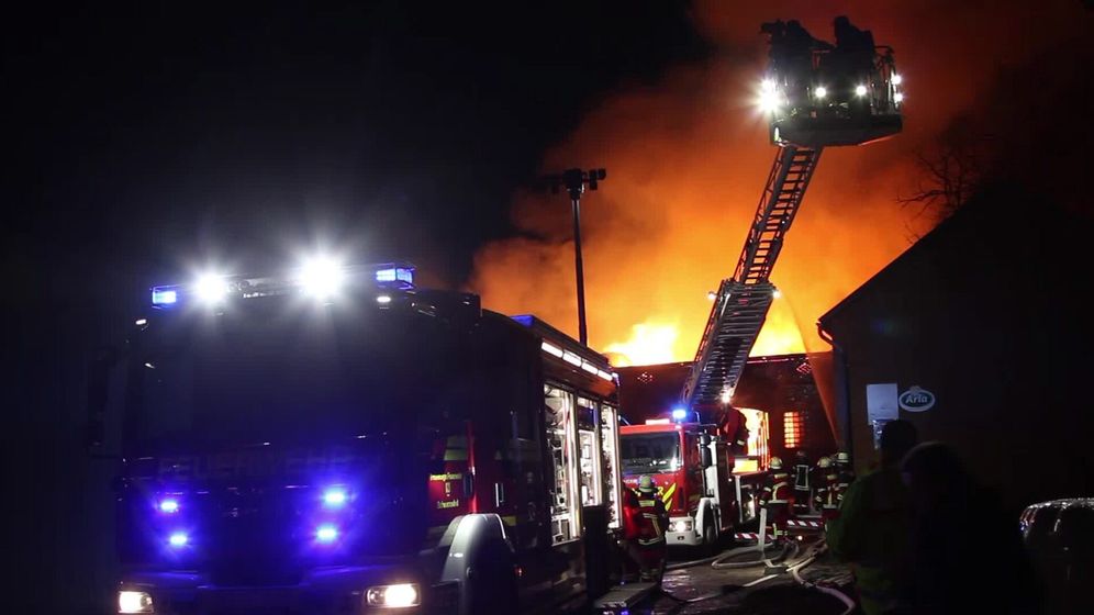 Feuerwehrleute auf Drehleiter löschen nachts einen Brand | Bild:picture alliance / peter wuest