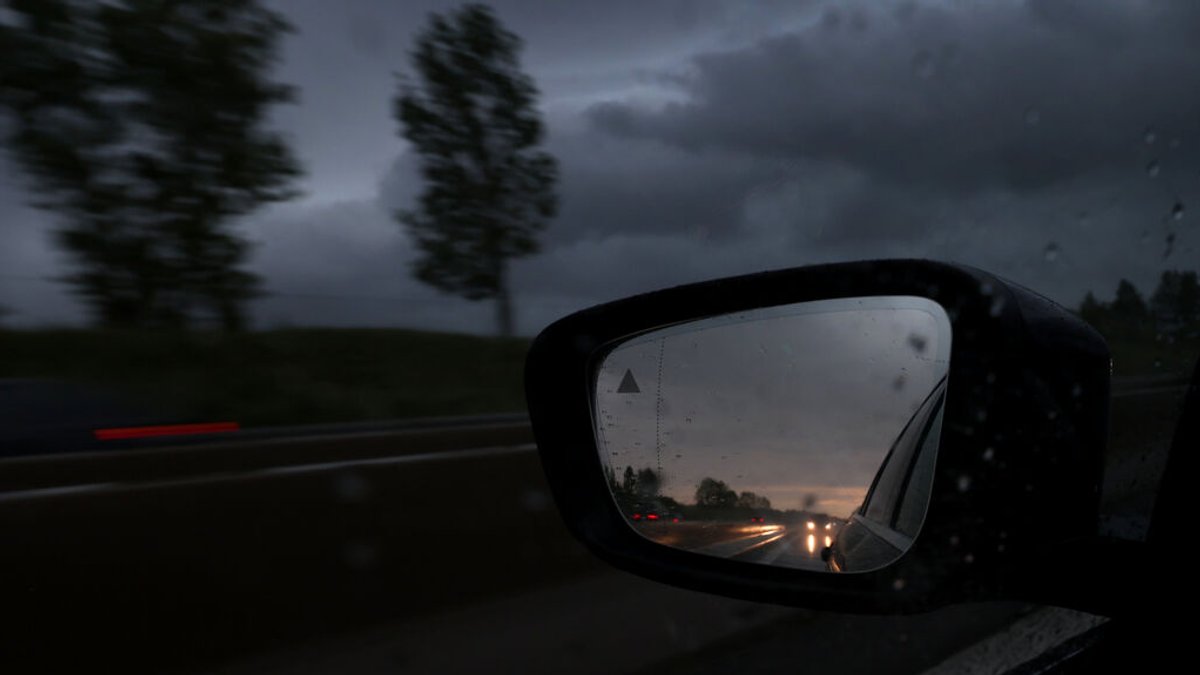 06.05.2024, München: Ein Auto ist während heftigen Regens in einem Rückspiegel auf der Autobahn 93 (A93) zu sehen. 