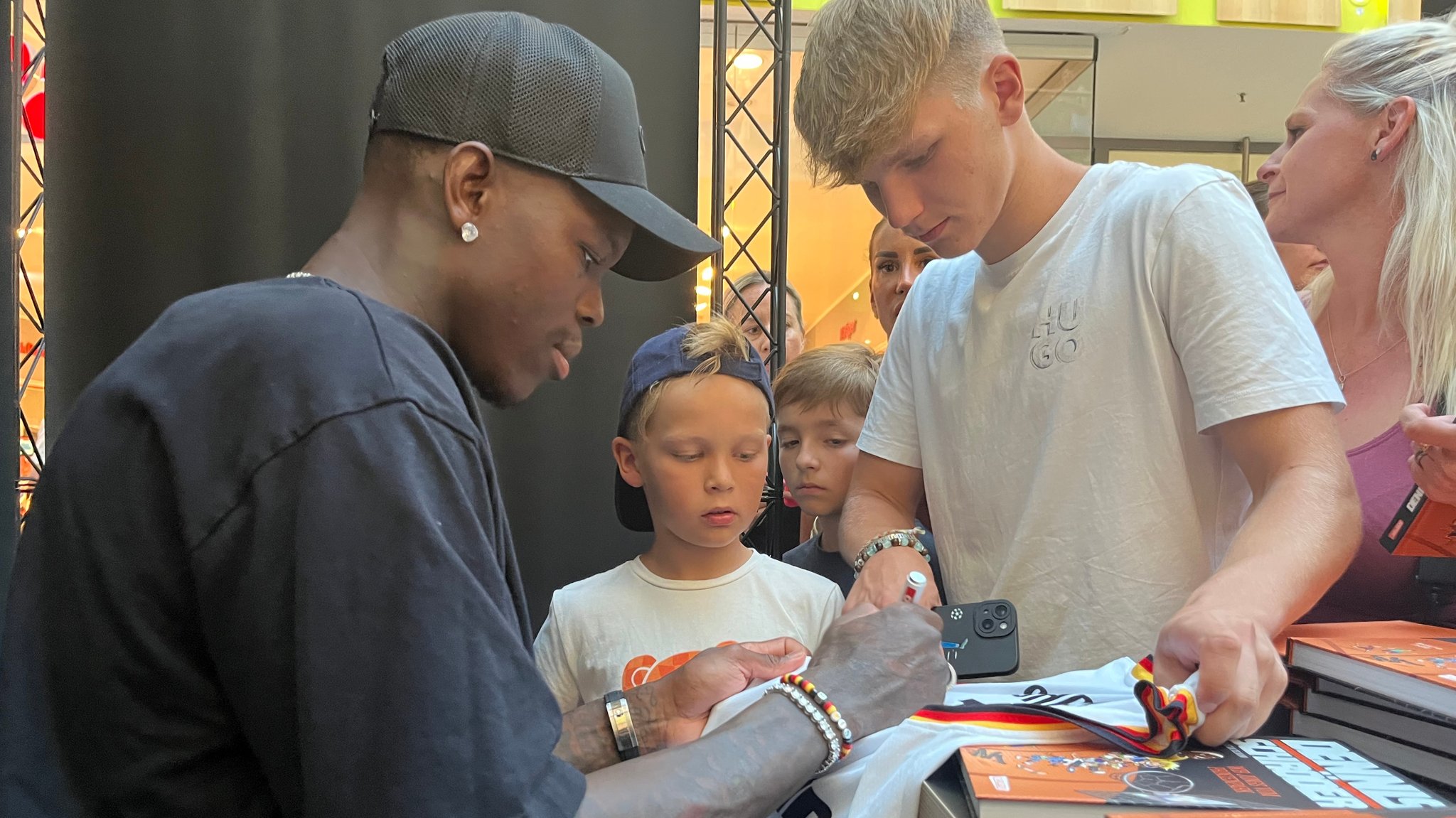 Dennis Schröder signiert Henry Ströll (Mitte) und seinem Bruder ein Tshirt.