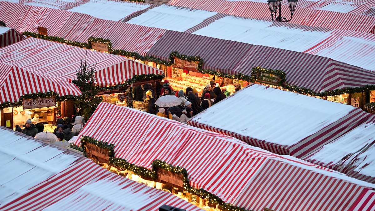 Rot-weiß gestreifte Dächer des Nürnberger Christkindlesmarktes, leicht mit Schnee bedeckt.