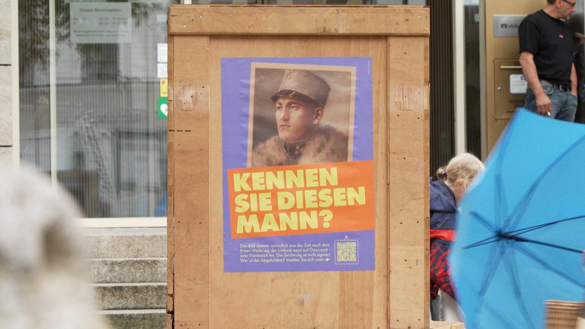 Ein Plakat hängt in der Passauer Fußgängerzone. Darauf zu sehen ist eine Kopie einer vermeintlichen Raubkunst.