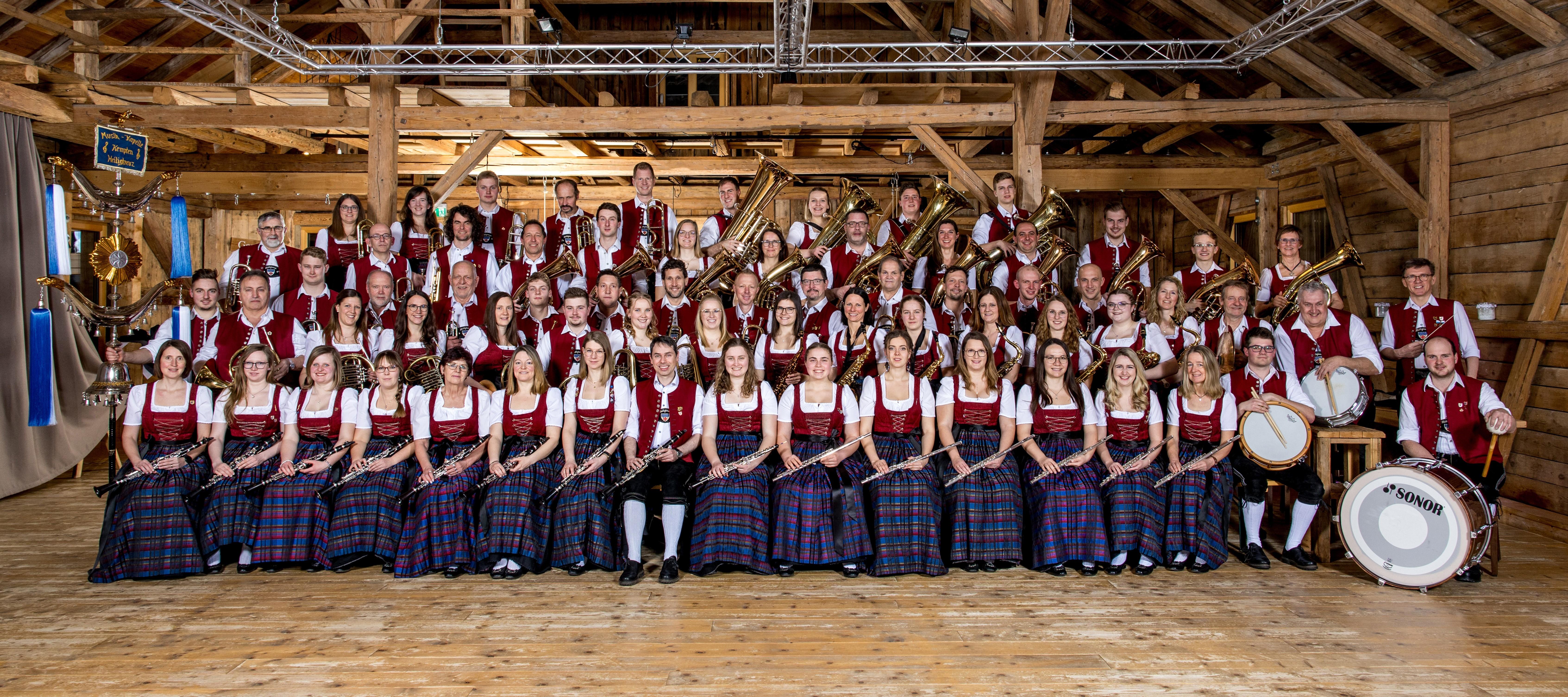 Musikerinnen und Musiker der Blaskapelle Heiligkreuz sitzen in Tracht und präsentieren ihre Instrumente