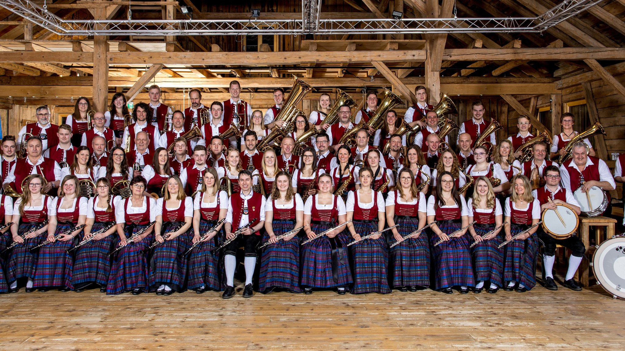 Musikerinnen und Musiker der Blaskapelle Heiligkreuz sitzen in Tracht und präsentieren ihre Instrumente