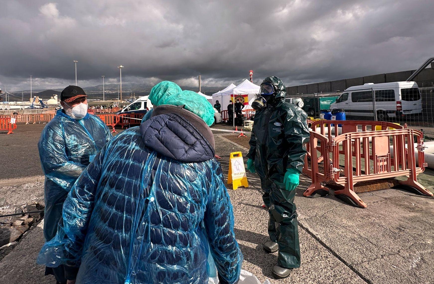 Personen in Schutzbekleidung und mit Masken gehen über das Hafengelände nach der Ausschiffung von dem vom Hantavirus betroffene Kreuzfahrtschiff MV Hondius im Hafen von Granadilla.