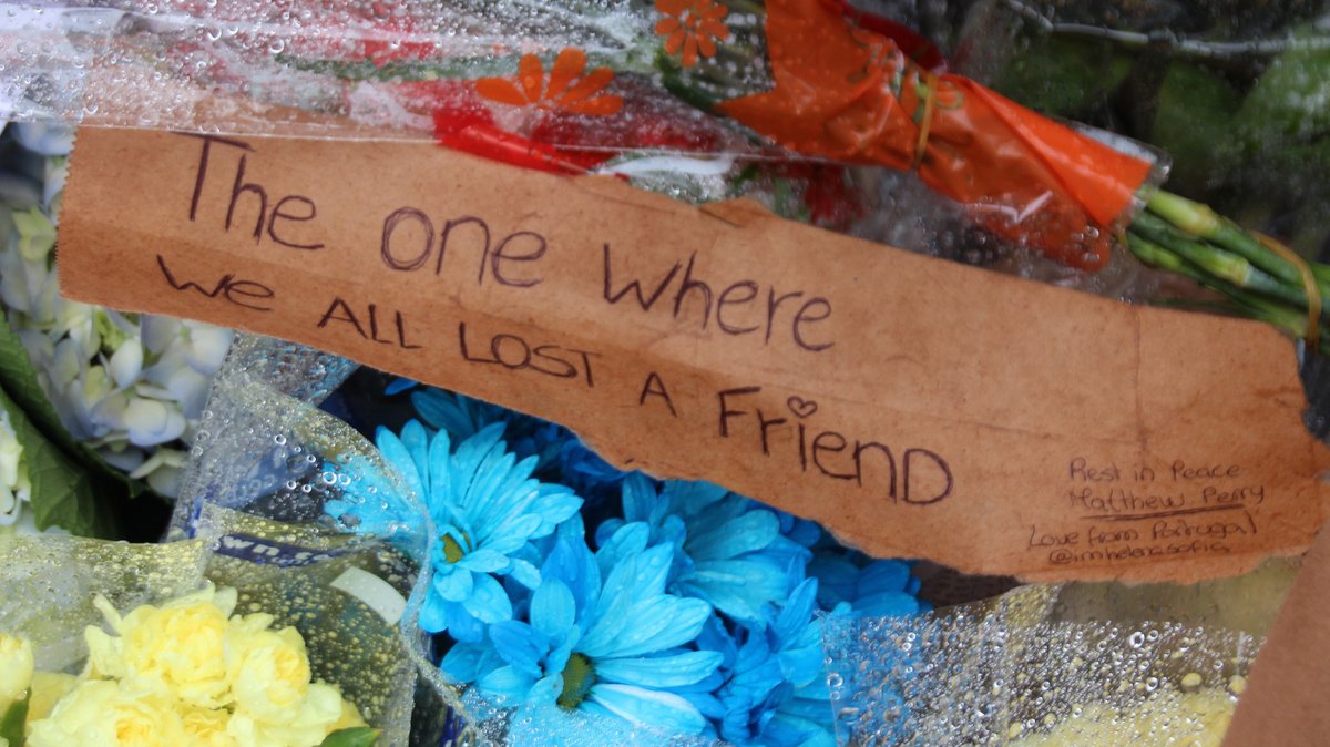 Blumen und Botschaften im Gedenken an den gestorbenen Schauspieler Matthew Perry vor dem "Friends"-Haus in New York. Auf einem Schild steht "The one where we all lost a friend" in Anspielung an die Betitelung der Serienepisoden von "Friends".