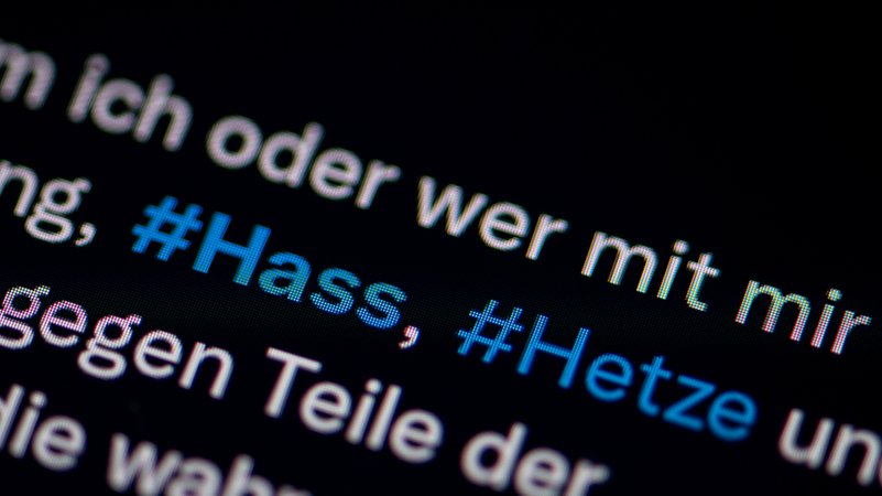Auf dem Bildschirm eines Smartphones sieht man die Hashtags "Hass" und "Hetze" in einem X-Post. (Archivbild)