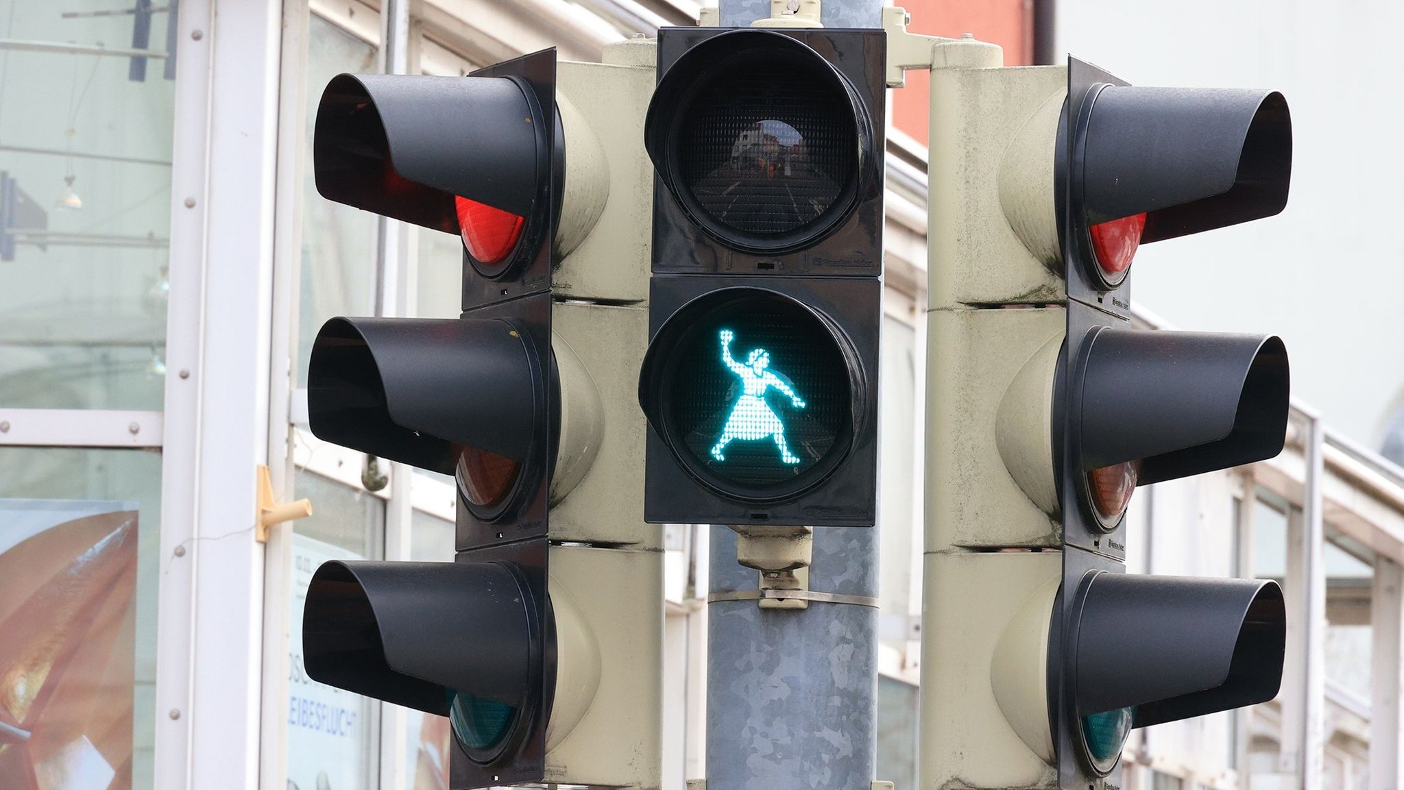 Auf einer grünen Fußgängerampel ist eine Frau zu sehen, die ein Kleid trägt und mit der rechten Hand einen Knödel wirft. | Bild: Stadt Deggendorf Auf einer grünen Fußgängerampel ist eine Frau zu sehen, die ein Kleid trägt und mit der rechten Hand einen Knödel wirft.