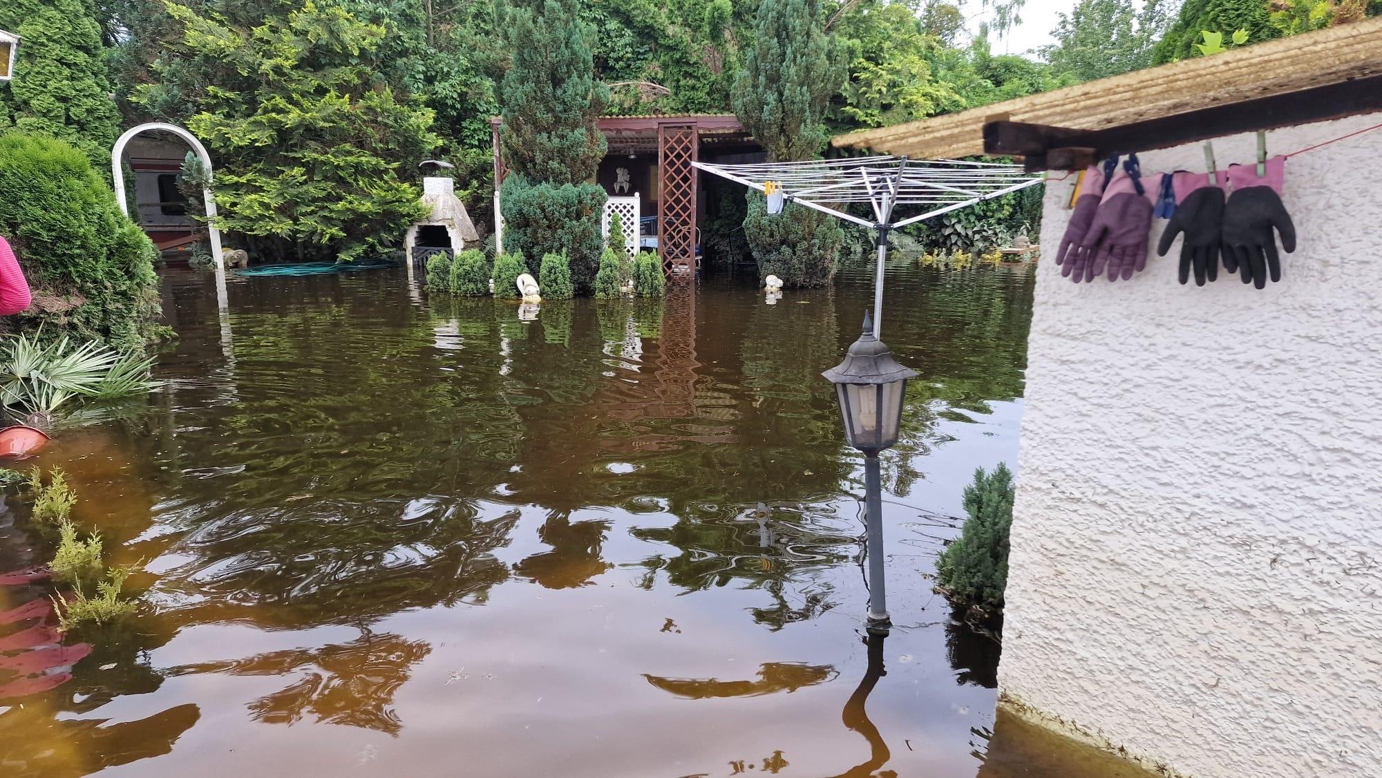 Das Zuhause von Karin Tuschhoff hat das Hochwasser Anfang Juni geflutet. Man sieht einen Garten, der durch die Wassermassen kaum mehr erkennbar ist.
