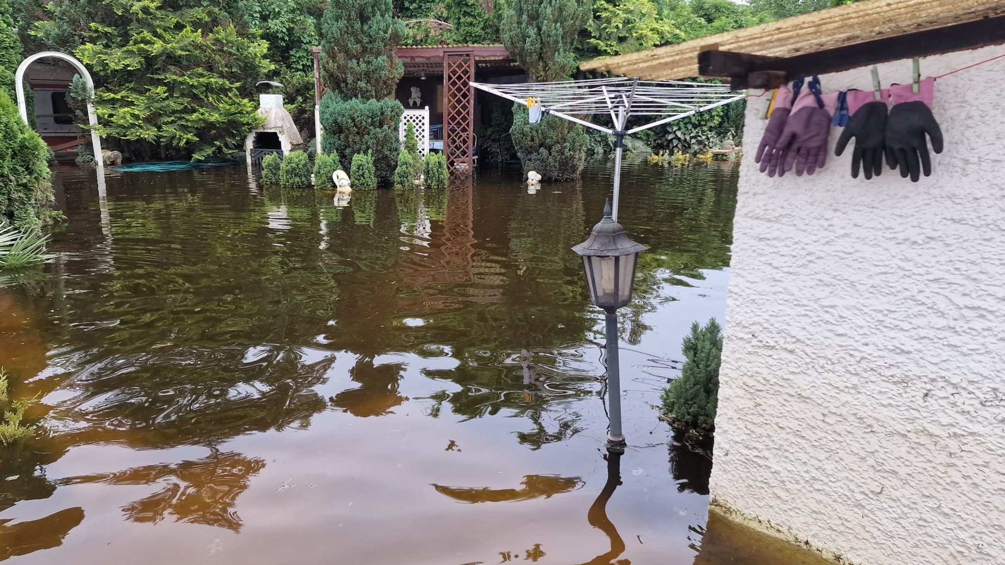 Das Zuhause von Karin Tuschhoff hat das Hochwasser Anfang Juni geflutet. Man sieht einen Garten, der durch die Wassermassen kaum mehr erkennbar ist.