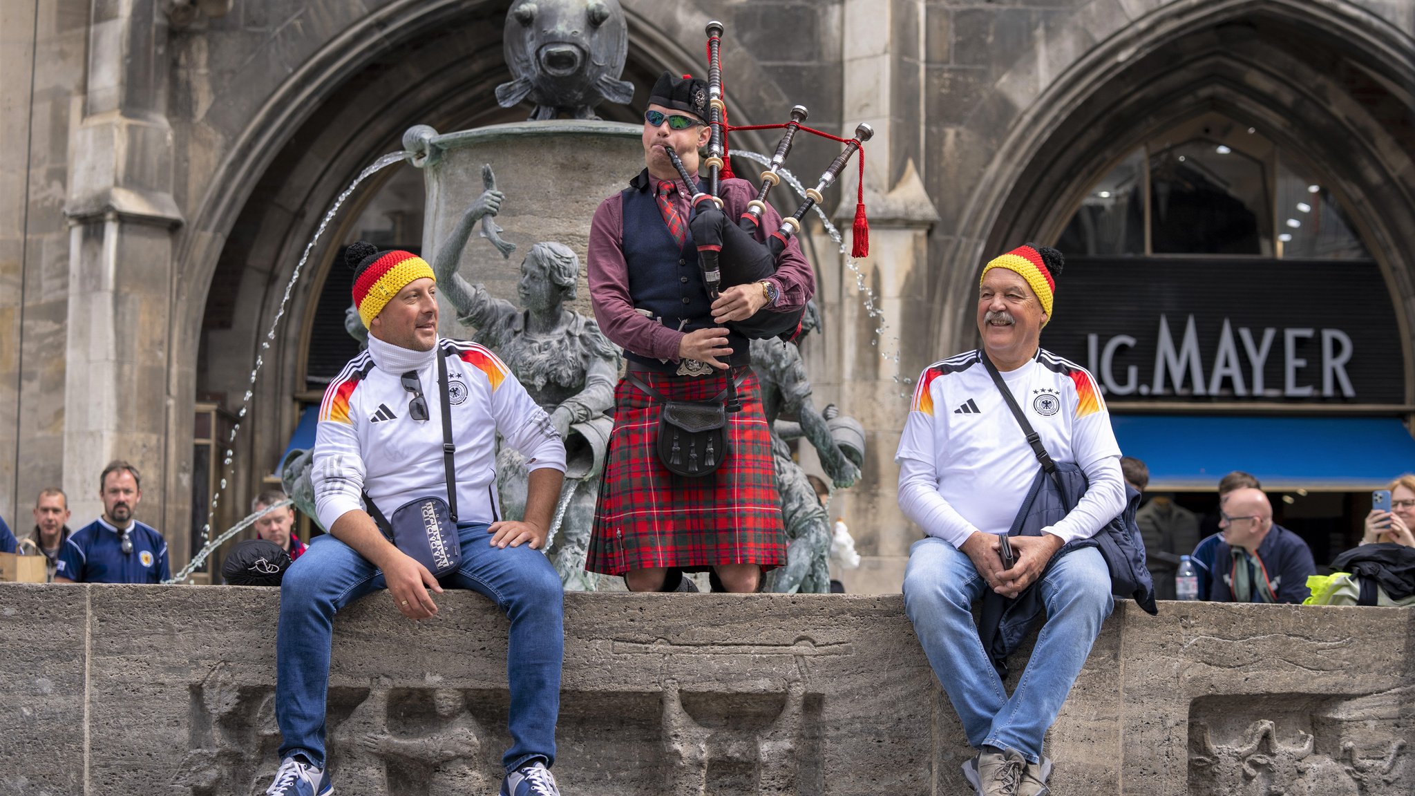 Ein Musiker in rotkariertem Kilt steht im Brunnen