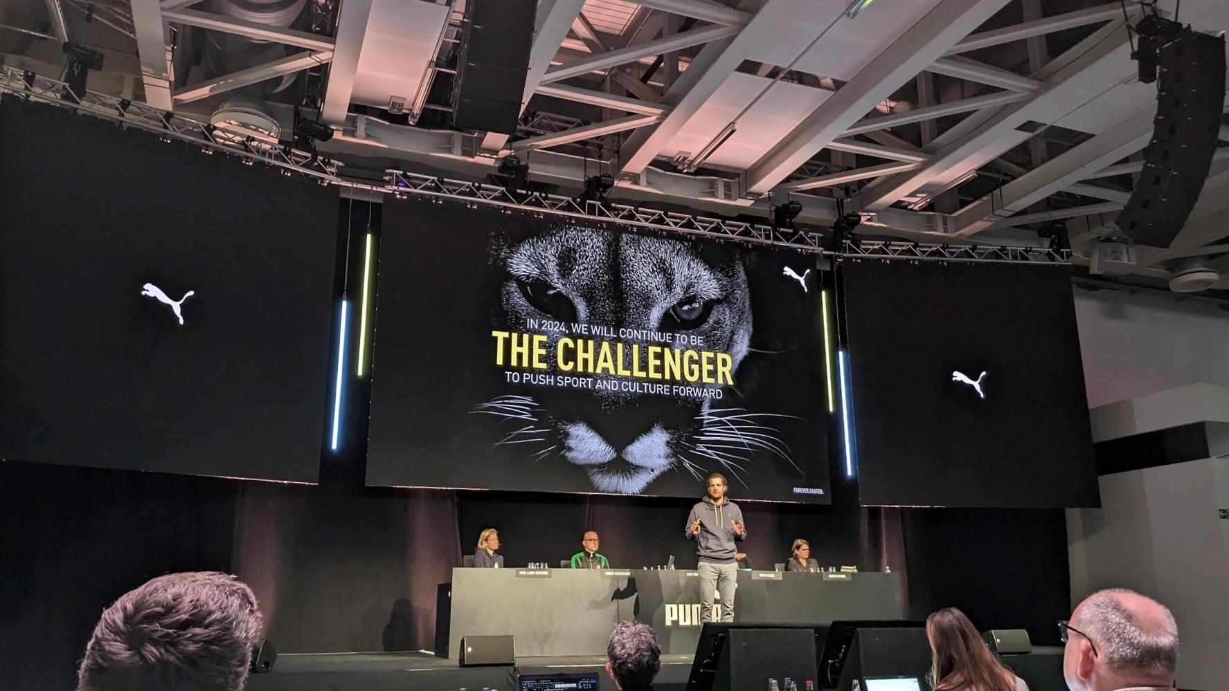 Puma-Chef Arne Freundt steht bei der Vorstellung der Jahreszahlen auf der Bühne vor einem Bild eines Pumas. 