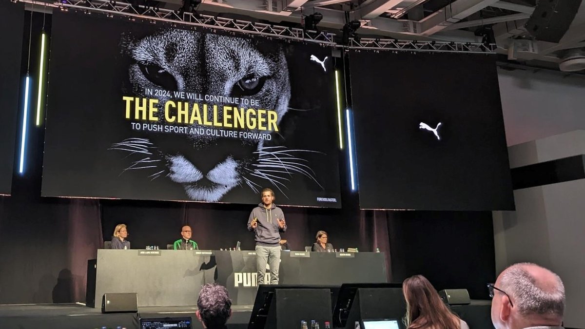 Puma-Chef Arne Freundt steht bei der Vorstellung der Jahreszahlen auf der Bühne vor einem Bild eines Pumas. 