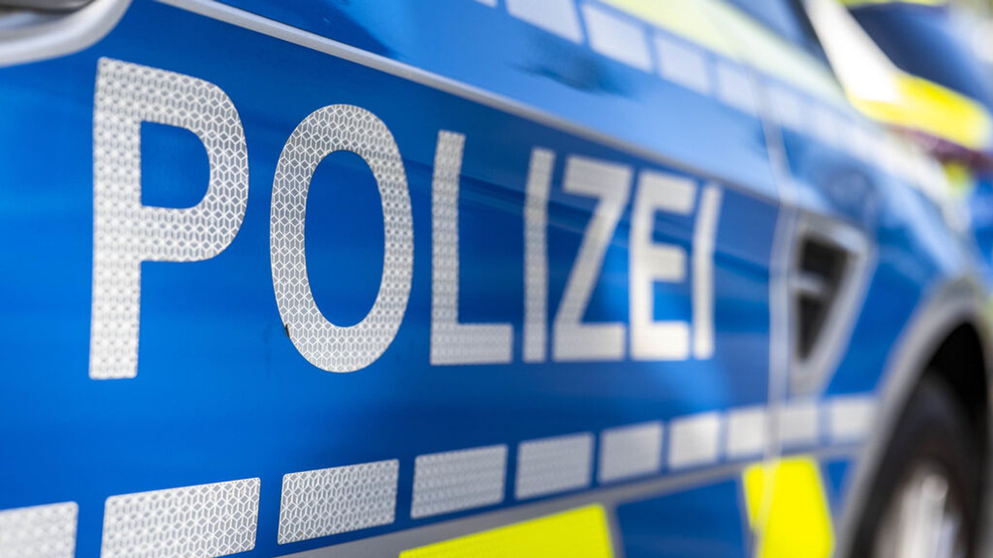 An der Tür von einem Streifenwagen steht der Schriftzug "Polizei". 