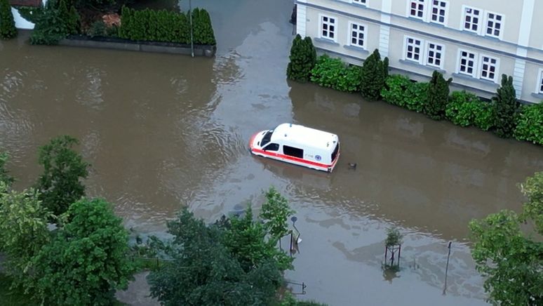 02.06.2024: Ein Krankenwagen fährt über eine überschwemmte Straße in Schrobenhausen im Landkreis Neuburg-Schrobenhausen. (Luftaufnahme mit einer Drohne) | Bild:picture alliance/dpa/tv7news | -