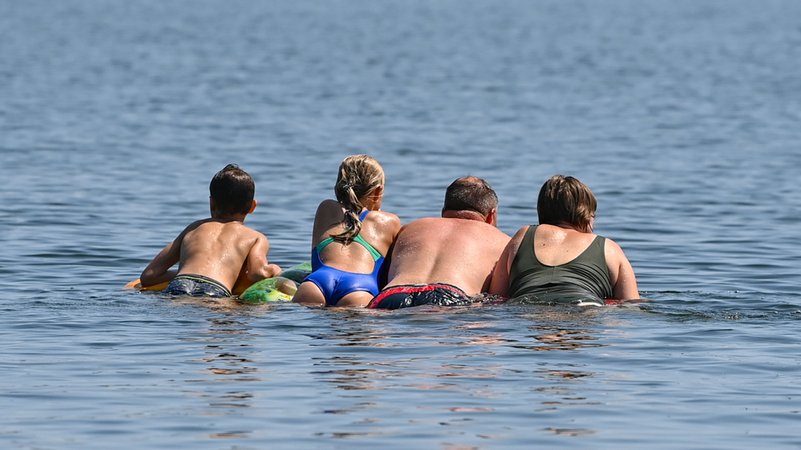 Eine Familie schwimmt auf einer Luftmatratze im Wasser eines Sees. | Bild: dpa-Bildfunk/Patrick Pleul Eine Familie schwimmt auf einer Luftmatratze im Wasser eines Sees.