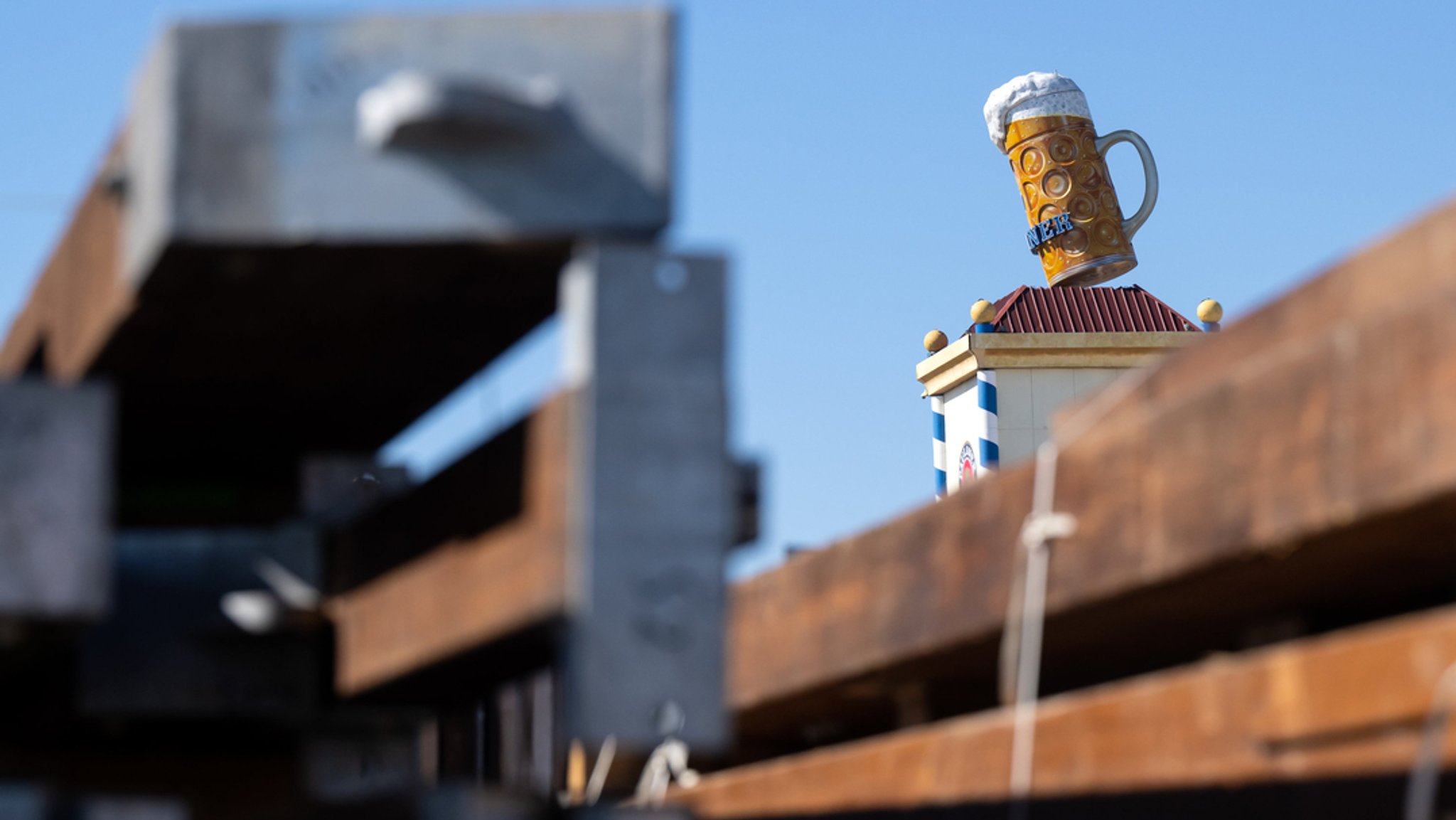 Ein übergroßer Bierkrug steht auf dem Oktoberfestgelände auf einem Turm.