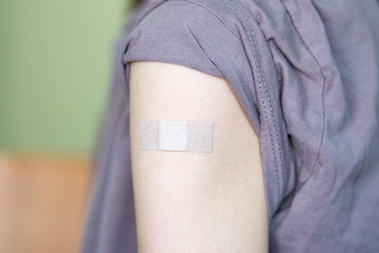 Auf dem Arm einer Jugendlichen klebt ein Pflaster, nachdem sie bei einem Kinder- und Jugendarzt mit dem Corona-Impfstoff Comirnaty von Biontech/Pfizer geimpft wurde.