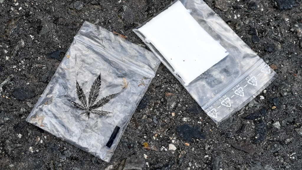 Zwei Plastiktütchen liegen auf dem Asphalt. In einem steckt ein Marihuanablatt.