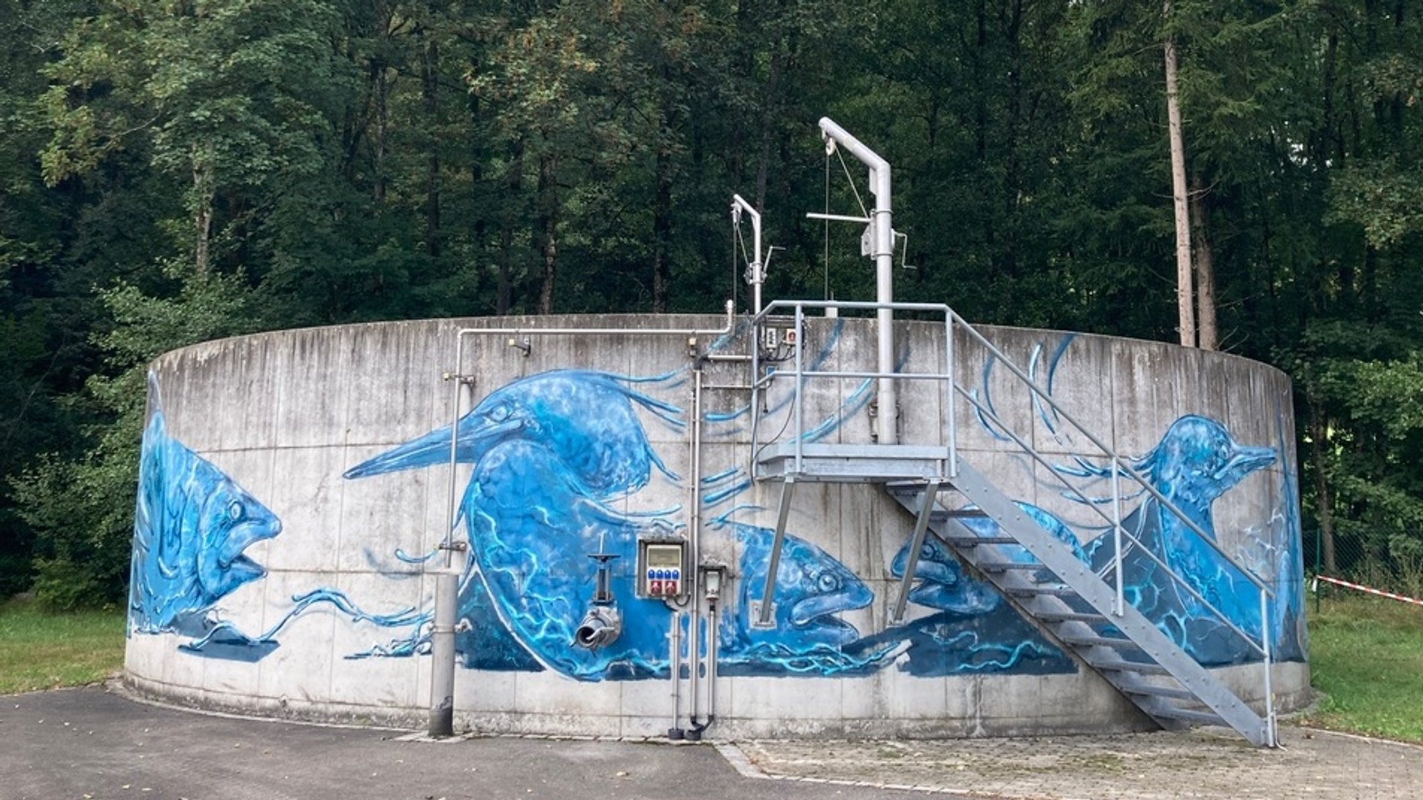 Eine Betonrotunde vor einem Waldstück, sie ist mit blauen Graffitis geschmückt. die Fische und Vögel abbilden. | Bild: Renate Haimerl Brosch Eine Betonrotunde vor einem Waldstück, sie ist mit blauen Graffitis geschmückt. die Fische und Vögel abbilden.