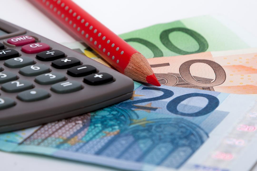 Ein Taschenrechner, ein Stift und Geldscheine liegen auf einem Tisch 