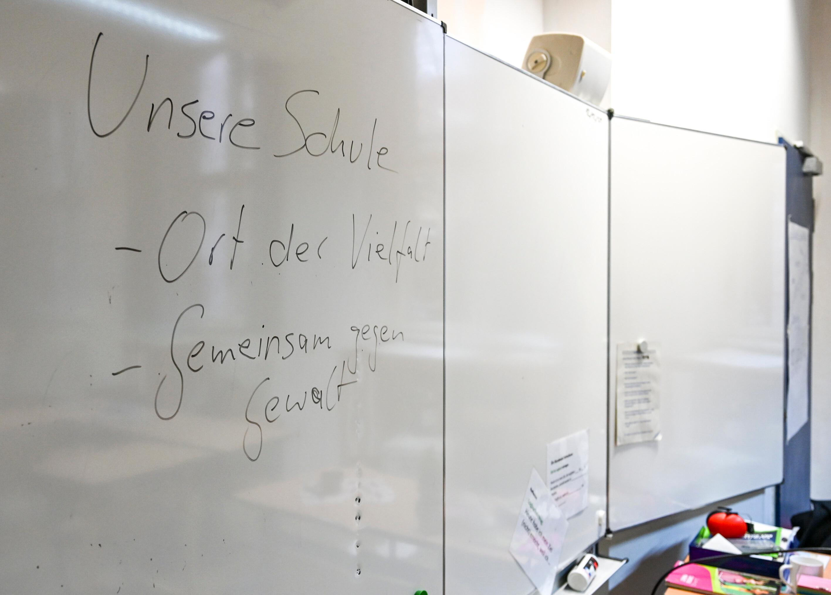 Symbolbild: "Unsere Schule - Ort der Vielfalt - Gemeinsam gegen Gewalt" steht auf einem Whiteboard.
