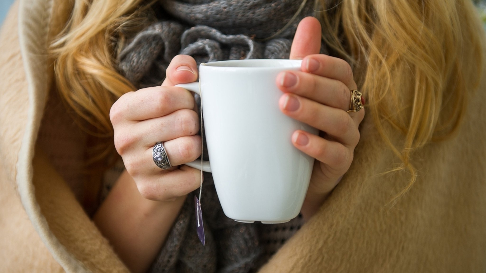 ILLUSTRATION - 20.10.2014, Niedersachsen, Hannover: Eine Frau wärmt sich in Hannover, in eine Decke gehüllt, an einer Tasse Tee. Manche wollen gar nicht mehr heizen, andere die Wassertemperaturen im Heizkessel minimieren. Was gut für den Geldbeutel ist, kann gefährlich für die Gesundheit werden. (Zu dpa: «Wasser- und Energiesparen - wie (un)gesund ist das?») Foto: picture alliance / dpa +++ dpa-Bildfunk +++