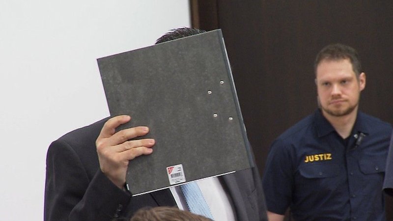 Der Angeklagte Dejan B., Ex-Partner von Alexandra R., mit einem Ordner vor dem Gesicht im Gerichtssaal. | Bild: BR24 Der Angeklagte Dejan B., Ex-Partner von Alexandra R., mit einem Ordner vor dem Gesicht im Gerichtssaal.