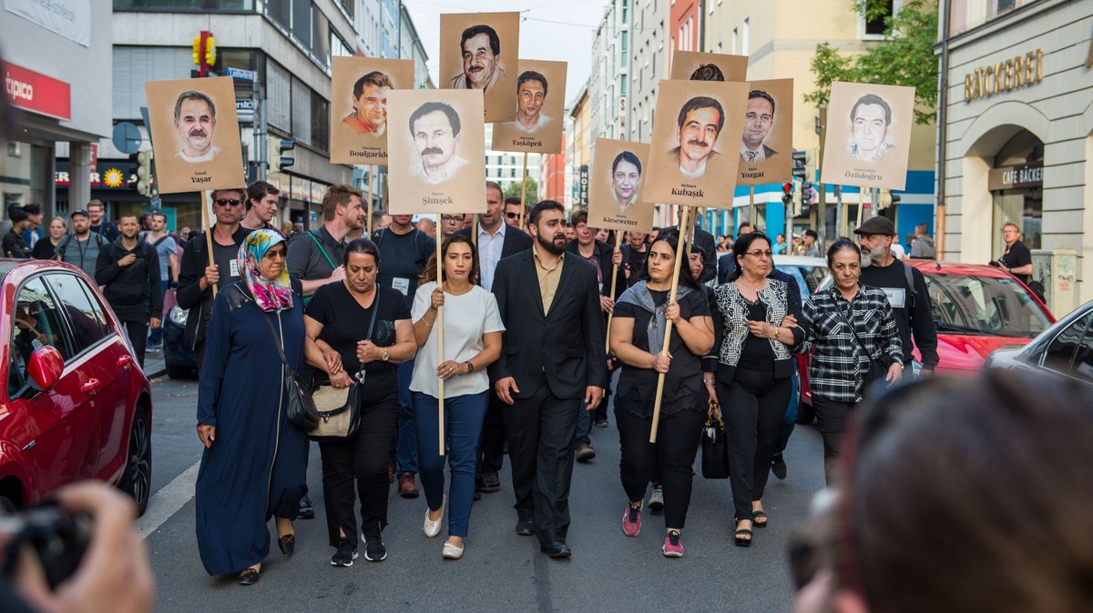 Angehörige halten bei einer Kundgebung am 11.07.2018 in München Schilder mit Portraitabbildungen der NSU-Opfer.