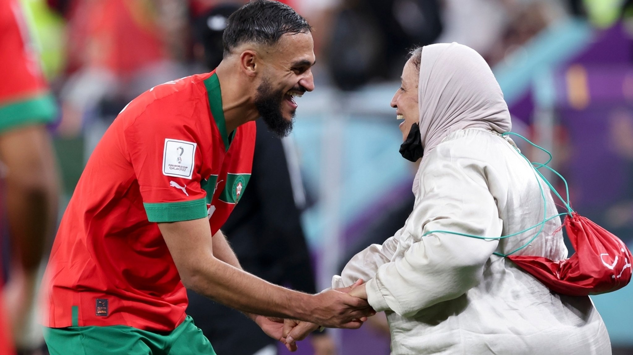 10.12.2022, Katar, Doha: Fußball, WM, Marokko - Portugal, Finalrunde, Viertelfinale, Al-Thumama Stadion, Marokkos Sofiane Boufal (l) tanzt nach dem Sieg gegen Portugal mit seiner Mutter auf dem Rasen. 
