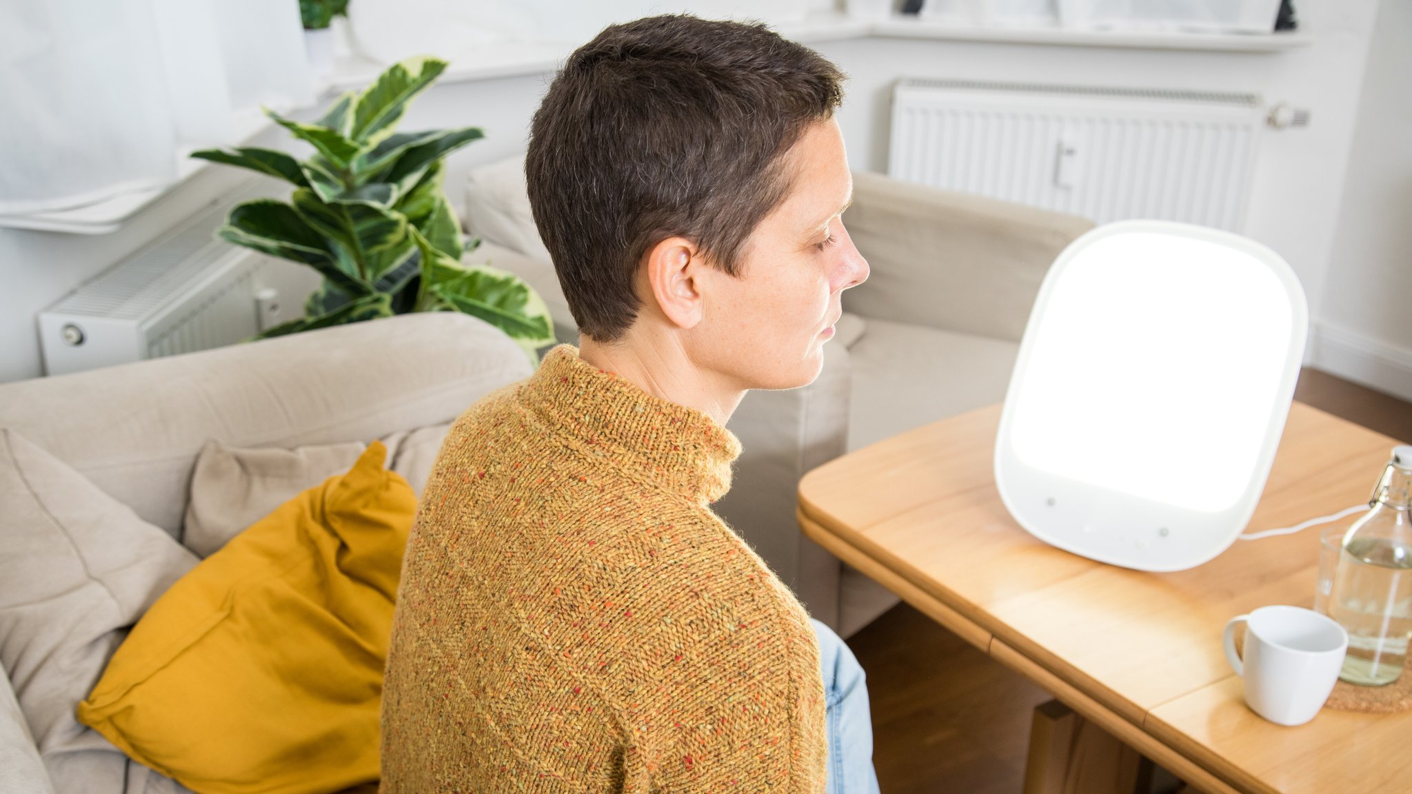 Eine Frau sitzt vor einer Tageslichtlampe